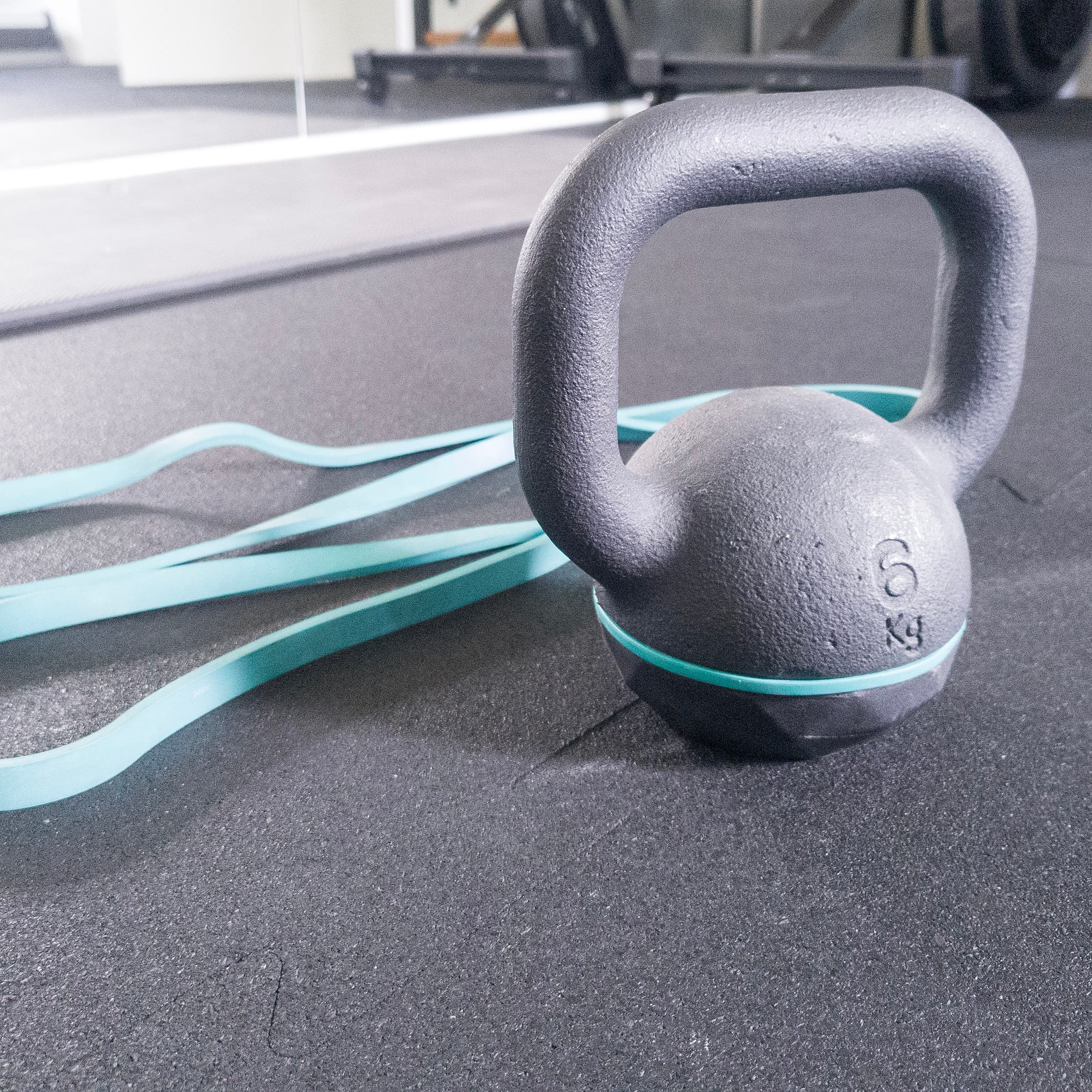 Kettlebell 6 kg i turkusowa guma oporowa na macie studia treningowego